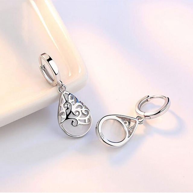 Sterling silver hoop drop earrings with teardrop pendant and white opal-style face.