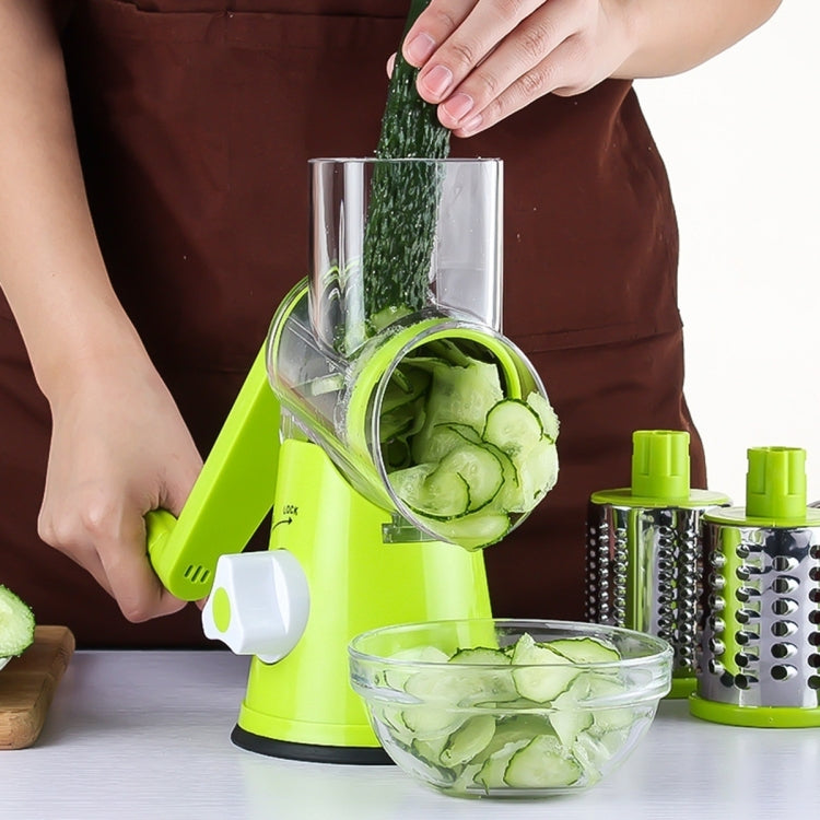 Green electric slicer with clear chute feeding cucumber slices into a bowl