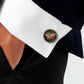 Round world map cufflink on white shirt cuff, black face with bronze continents