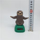 Solar-powered dancing sloth figure on green solar base, arms out, smiling face