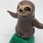 Solar-powered dancing sloth toy close-up: smiling brown sloth on green solar base