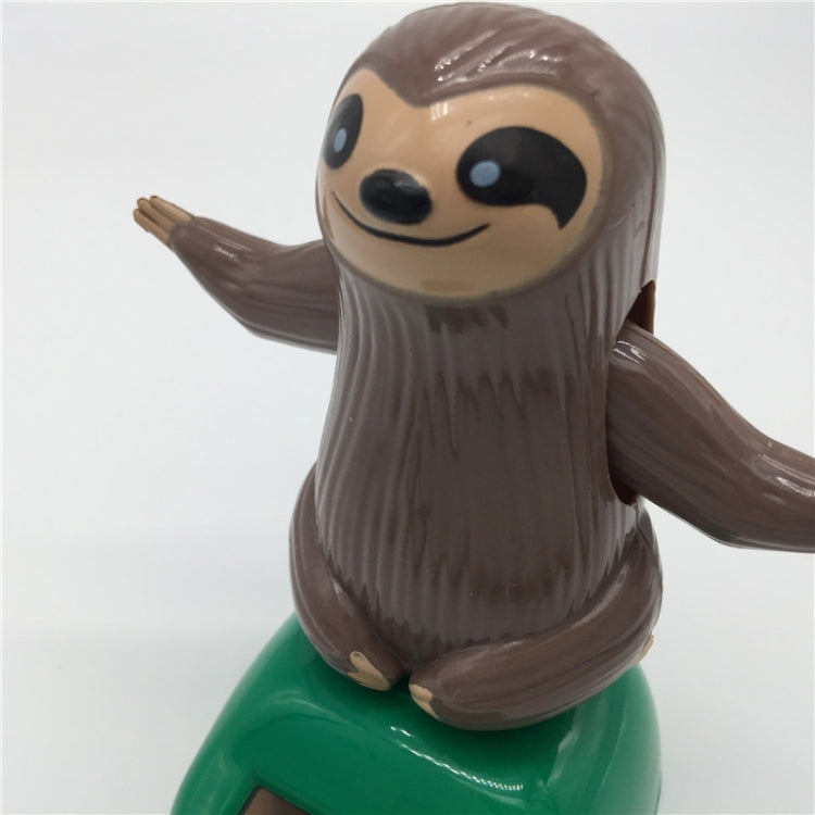 Solar-powered dancing sloth toy close-up: smiling brown sloth on green solar base