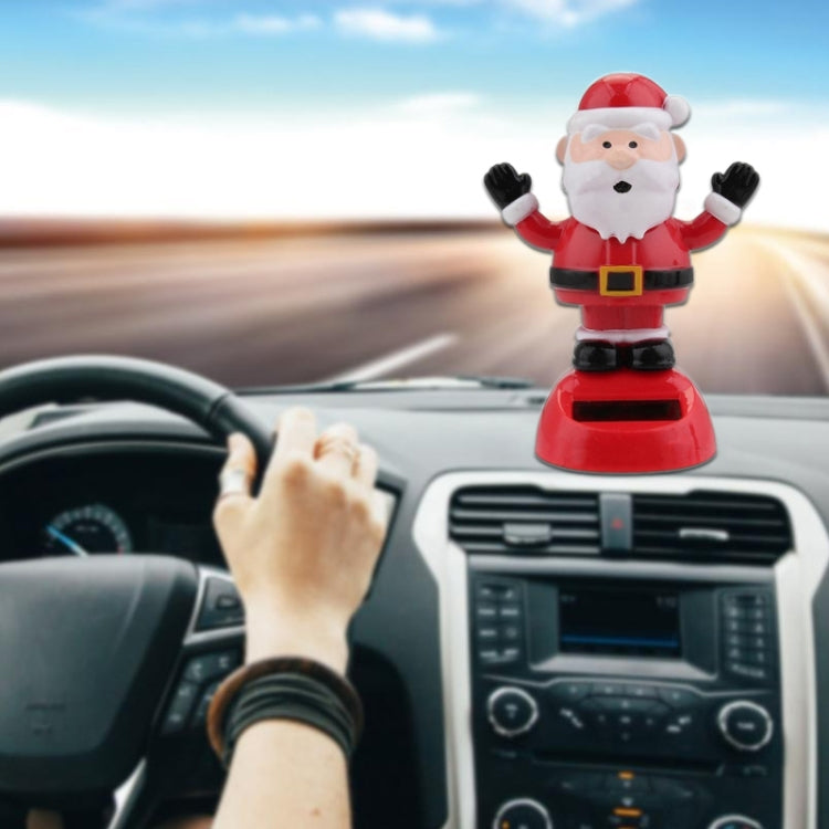 Santa Claus solar decoration with raised arms, red suit, and white beard on base