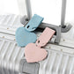 Blue and pink heart-shaped luggage tags clipped to a suitcase handle