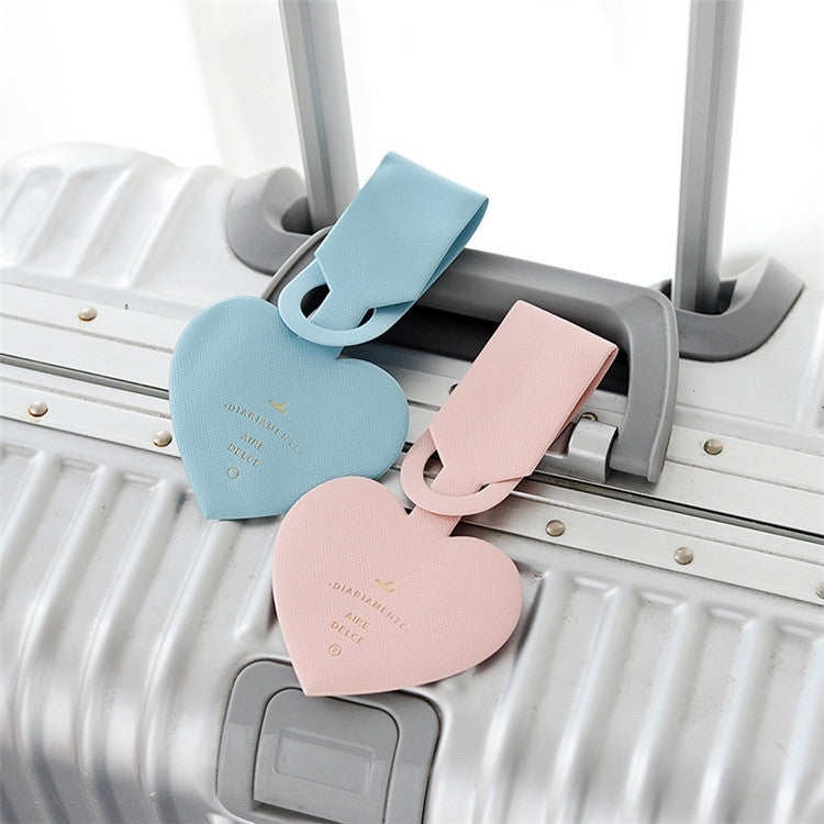 Blue and pink heart-shaped luggage tags clipped to a suitcase handle