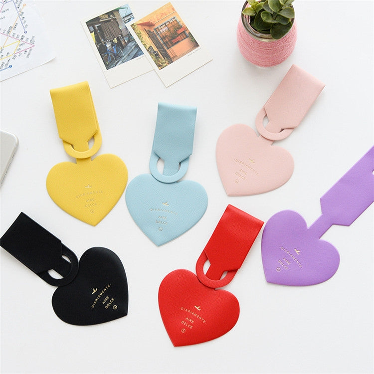 Mixed-color heart-shaped luggage tags laid flat, each with a name card label