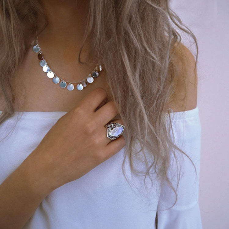 Silver oval gemstone ring with filigree detailing worn on finger