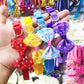 Adjustable pet bell collars with polka-dot bows in multiple colors held in hand