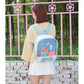 Mini transparent backpack in light blue with cartoon patch and bow accent, worn from behind