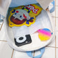 Transparent mini backpack open with cartoon front patch, showing items inside