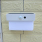 White solar wall light mounted on textured wall with solar panel and sensor