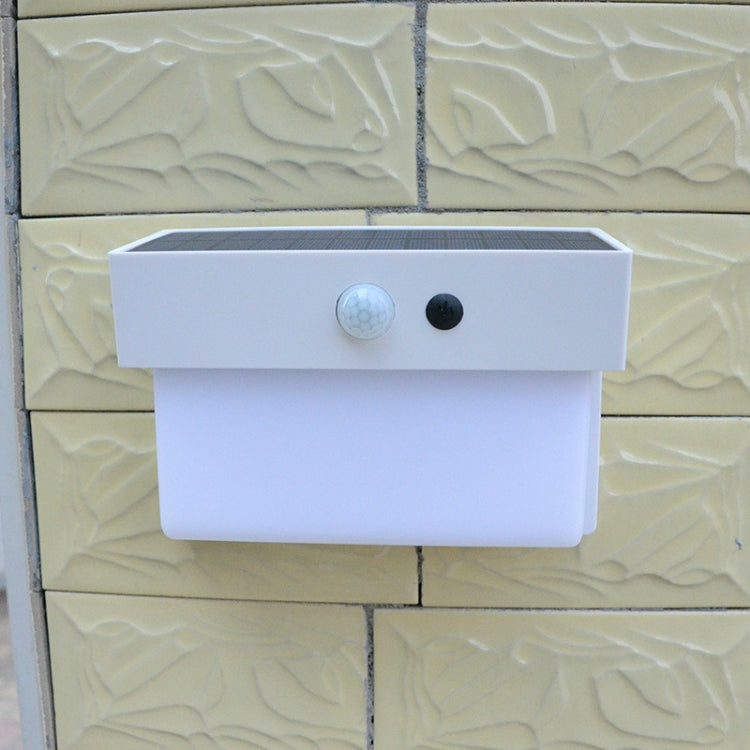 White solar wall light mounted on textured wall with solar panel and sensor