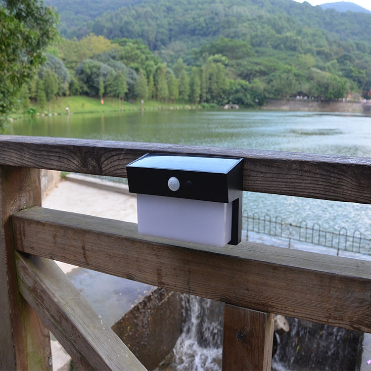 White solar wall light on wooden fence rail with round motion sensor
