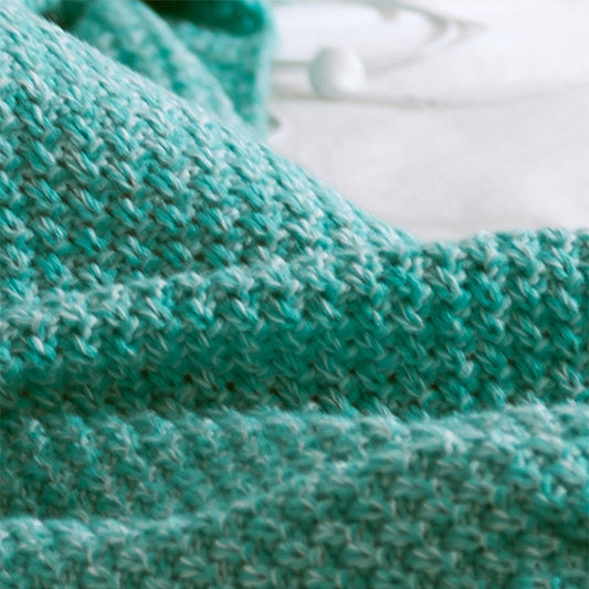Knitted mermaid tail blanket in teal, close-up of textured fabric weave