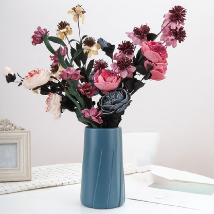 Blue plastic table vase with fluted sides, filled with faux flowers