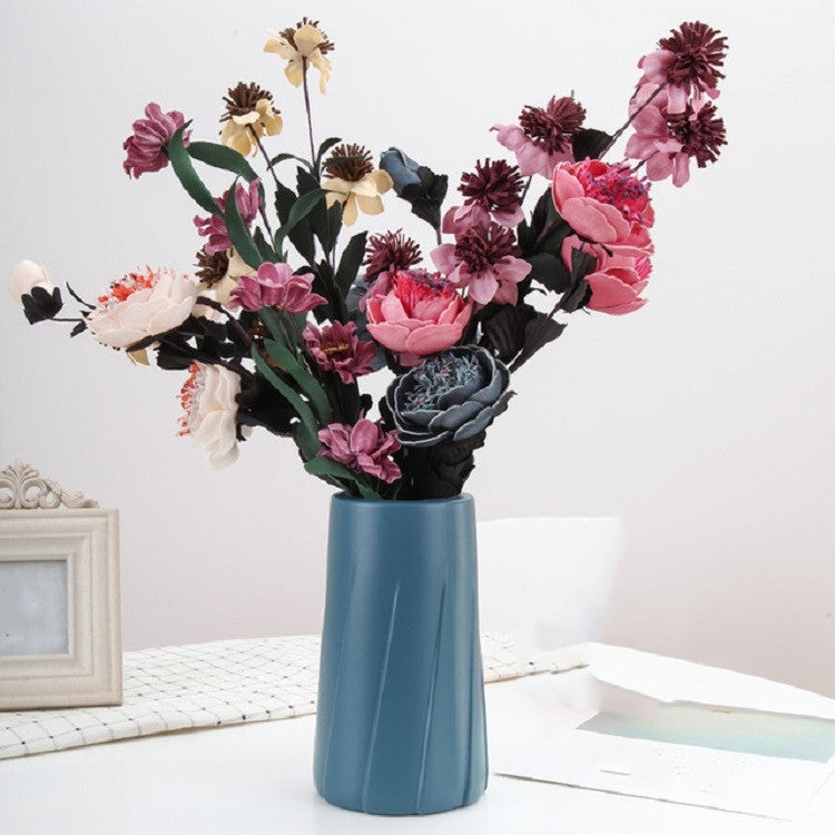 Blue fluted plastic vase for table decor, topped with faux flower stems
