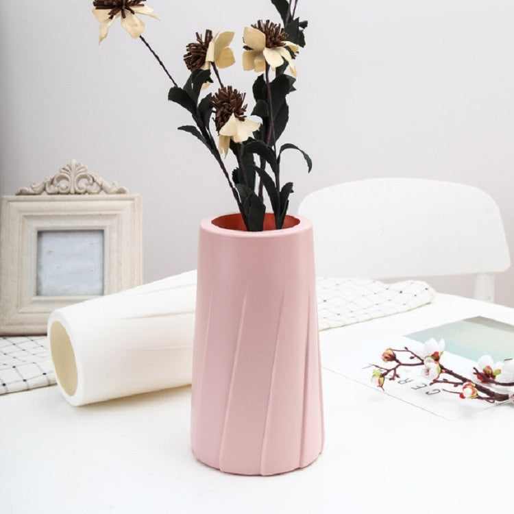 Pink plastic table vase with fluted sides, holding faux flower stems