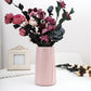 Pink plastic vase with fluted sides, filled with a faux flower bouquet