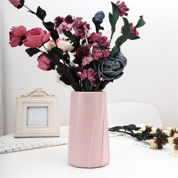 Pink plastic vase with fluted sides, filled with a faux flower bouquet
