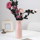 Pink ribbed plastic vase holding artificial flowers, tall desktop decoration