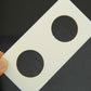 Close-up of a coin protector card with two round cutouts held by hand