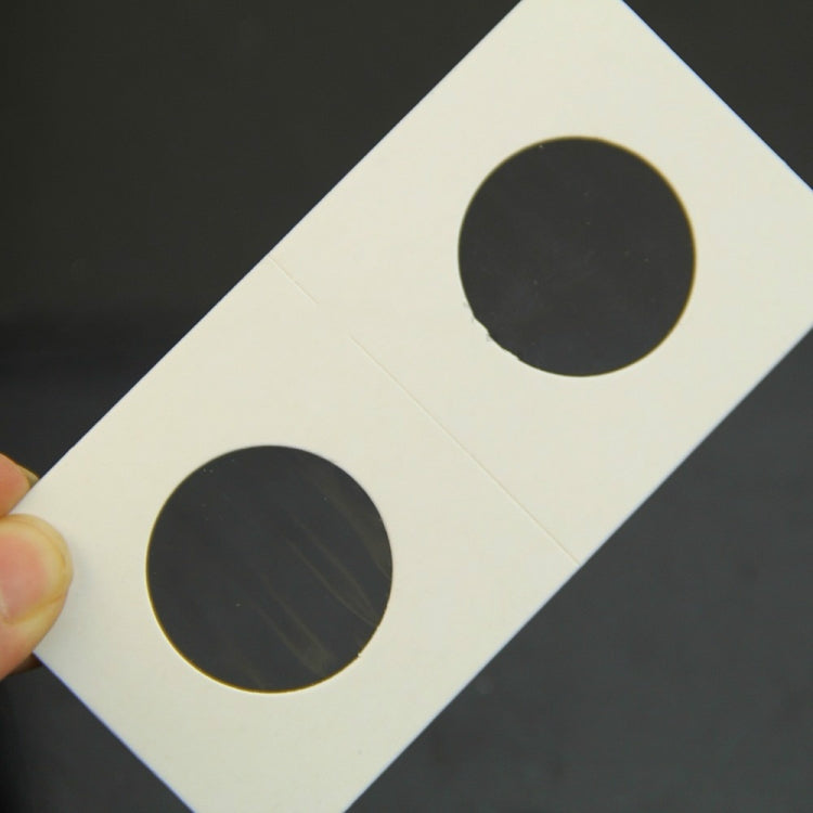 Close-up of a coin protector card with two round cutouts held by hand