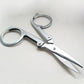 Folding scissors with oval finger rings and pointed blades, silver metal frame