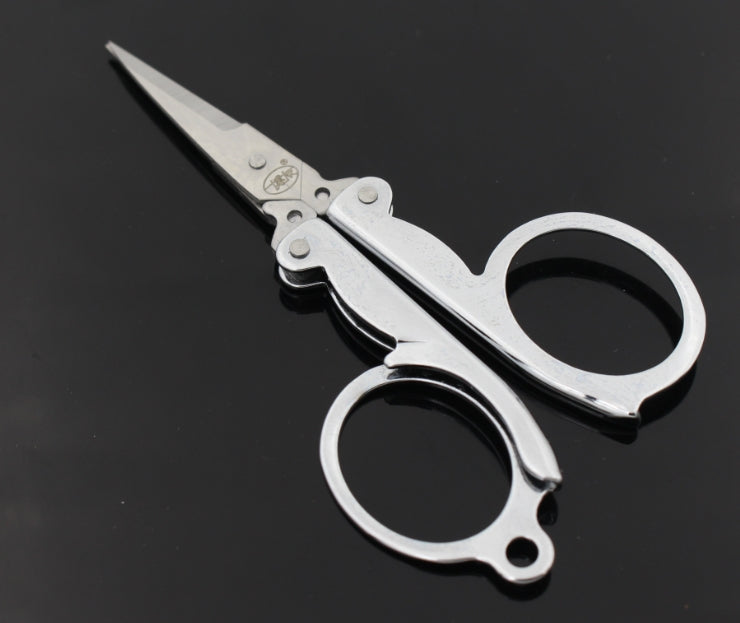 Compact folding scissors with finger rings and pointed blades, silver metal with black accents