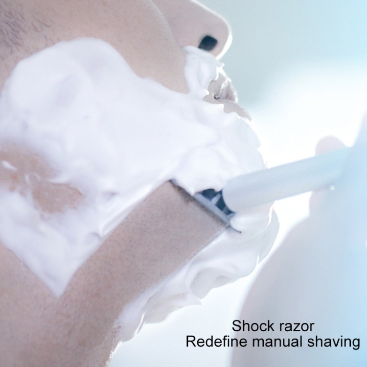 Handheld manual multi-shock razor with shaving cream, held by a hand