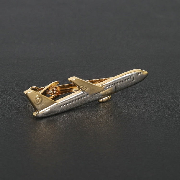 Gold airplane tie clip close-up on dark surface