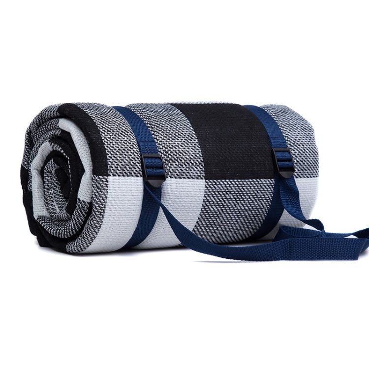 Rolled outdoor camping mat with navy, gray, and white plaid stripes, held by blue straps