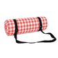 Rolled outdoor camping mat with white and red check pattern, secured by black straps