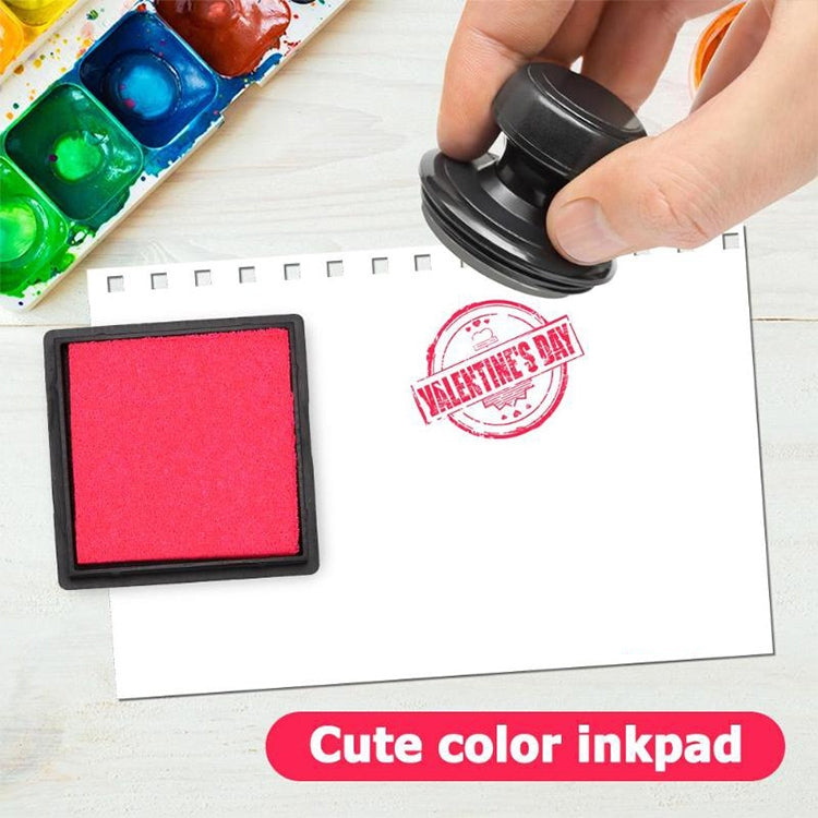 Red square ink pad on black base beside stamped white paper
