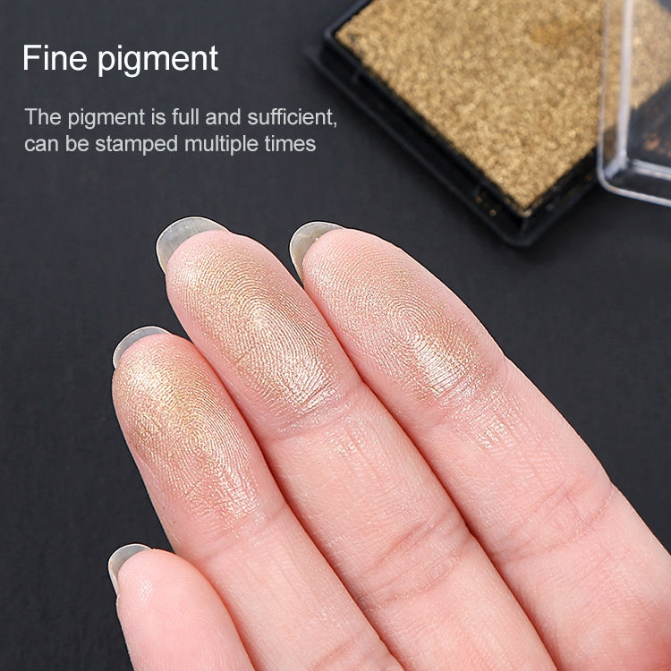 Close-up of tan ink pad corner and sponge texture beside fingertips