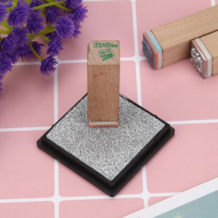Gray square ink pad on black base, textured sponge ready for stamping