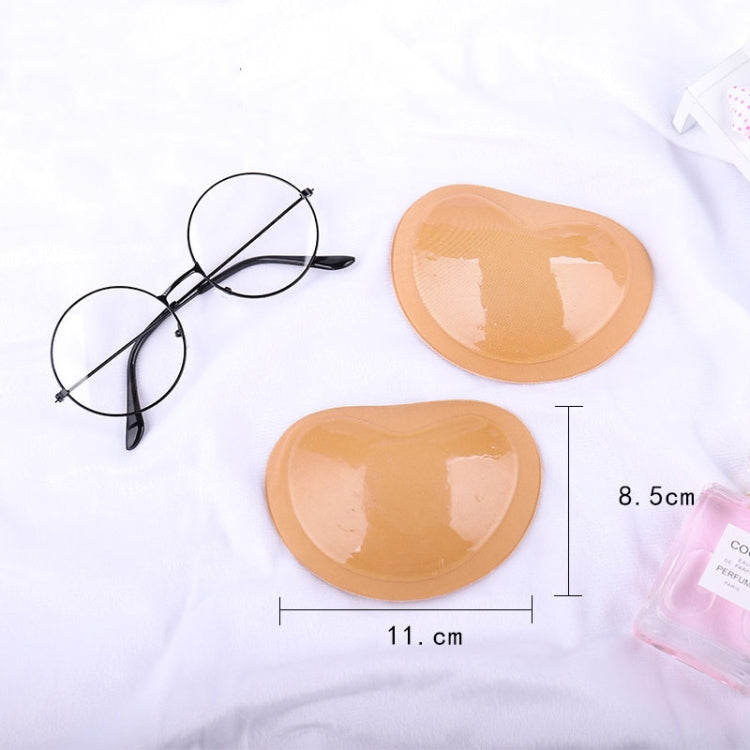 Two skin-tone silicone nipple cover pads with size markings on a flat surface.