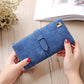 Blue suede-style clutch wallet phone bag with flap strap and gold-tone clasp; held up.