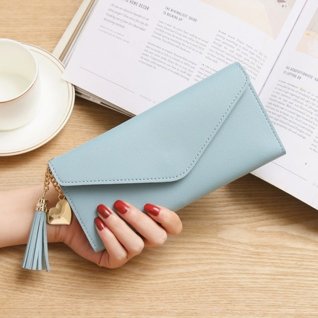 Light gray long zipper clutch wallet with tassel charm and gold-tone chain closeup