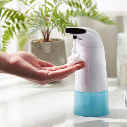 Automatic foam soap dispenser with white body and blue base, hand dispensing lather