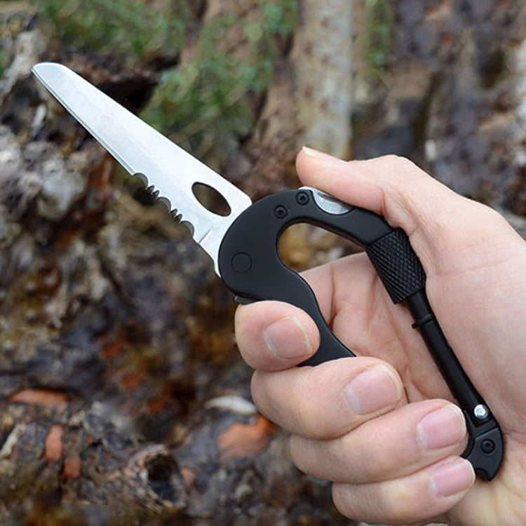 Black D-ring carabiner multitool keychain with serrated blade held in hand.