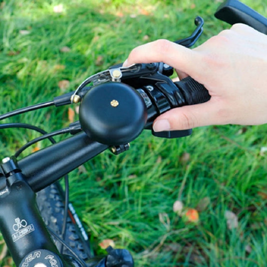 Black bicycle bell on handlebars with dome button and hand-ready grip