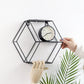 Black hexagonal hanging wall shelf holding a round clock on the shelf