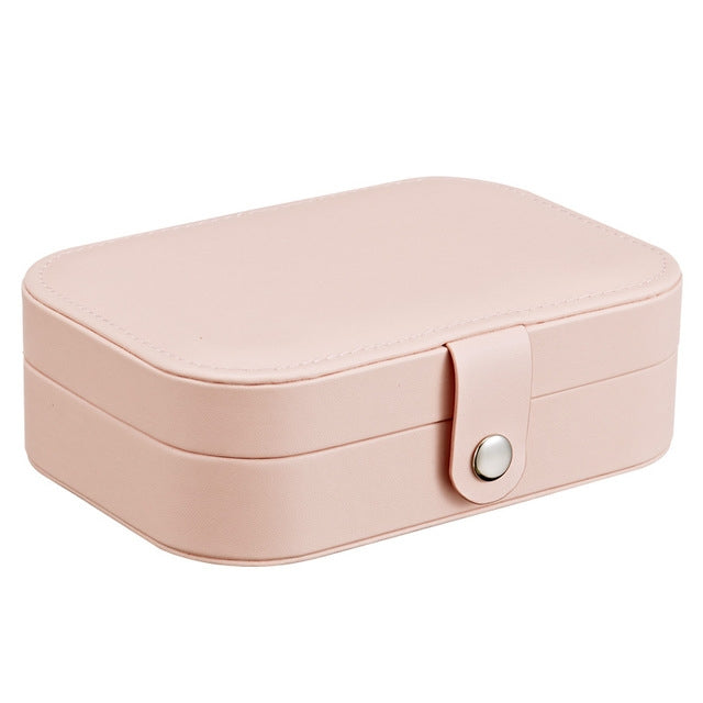 Portable jewelry storage box in blush pink with hinged lid and oval clasp.