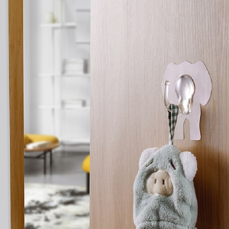 Elephant wall hook mounted on a light wood panel, holding a towel loop