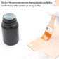 Flat paint brush with orange nylon bristles near a paint jar