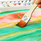 Flat paint brush applying orange paint on artwork with visible bristles