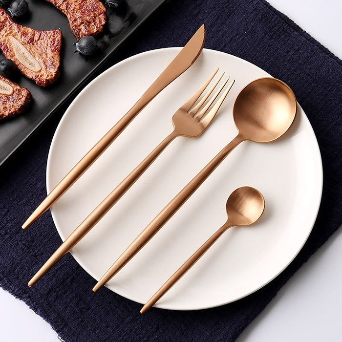 Rose gold stainless steel cutlery set: knife, fork, and spoon on white plate