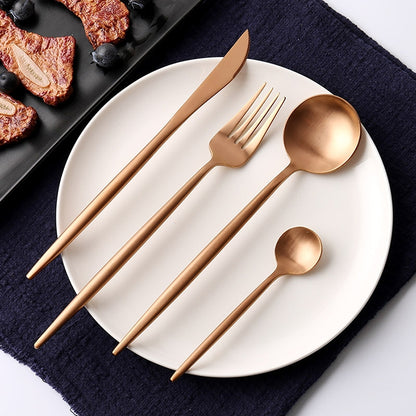 Rose gold stainless steel cutlery set: knife, fork, and spoon on white plate