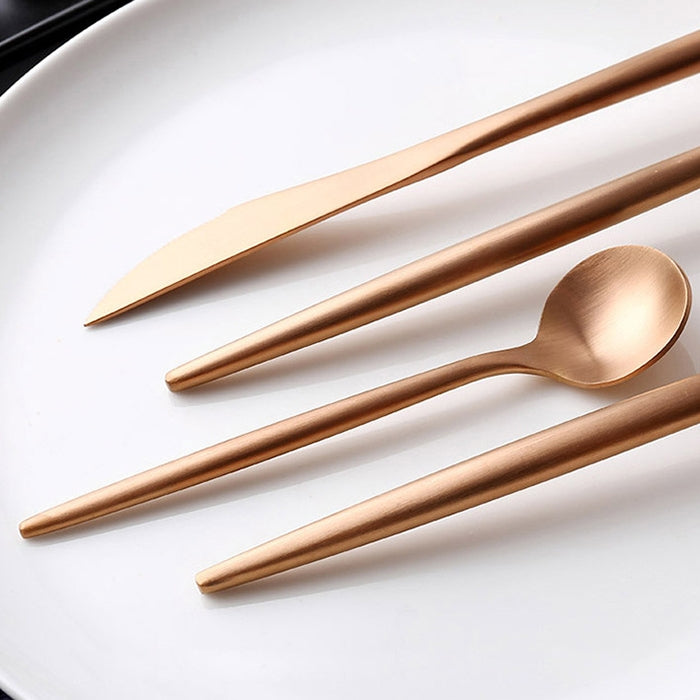 Rose gold stainless steel cutlery: knife, fork, and spoon on white plate