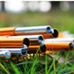 Orange aluminum tent poles with blue connector joints on outdoor grass